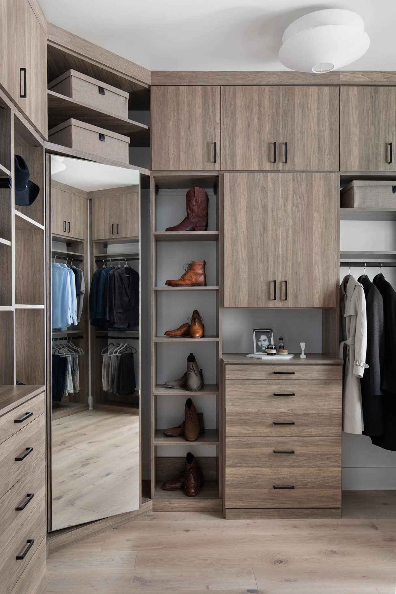 Wood finishes and black metal hardware accents define the custom closet aesthetic